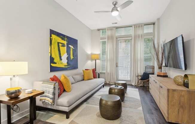 a living room with a gray couch and a yellow painting