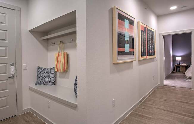 A hallway with a bench and two paintings on the wall.