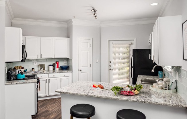 a kitchen with white cabinets and a counter top with black appliances