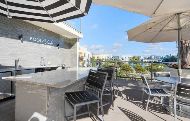 A pool bar with a striped umbrella and chairs.