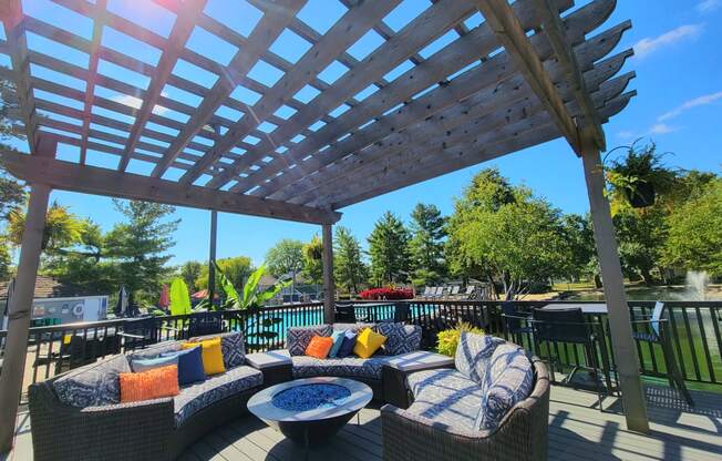 a pergola on a deck with couches and a table