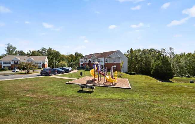 A playground with a yellow slide is in the middle of a grassy area.