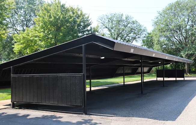 A black carport with a metal roof and a metal fence.