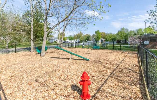 A red fire hydrant sits on a playground.