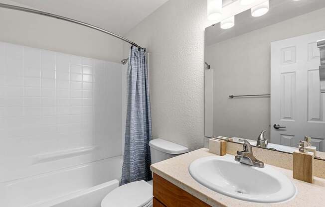 A white bathroom with a toilet, sink, and shower.
