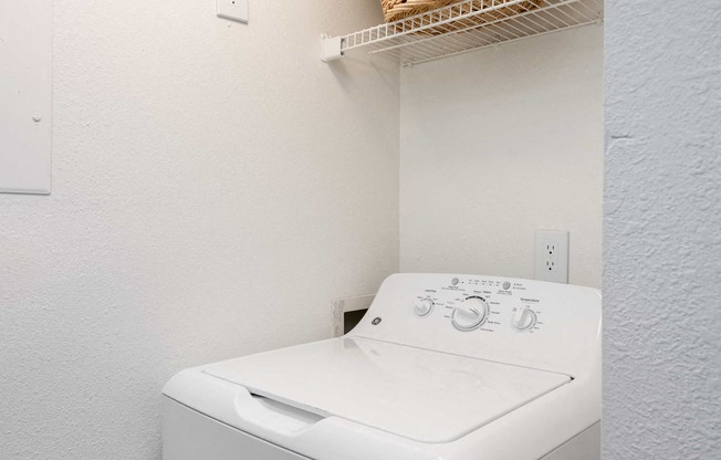 a white washer and dryer in a laundry room with a basket on top