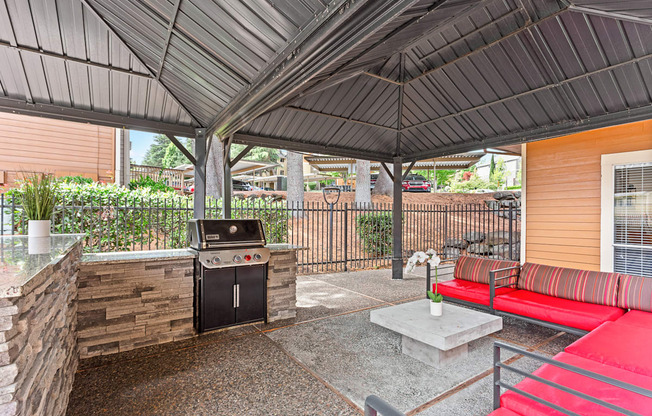 A patio with a grill and a red couch.