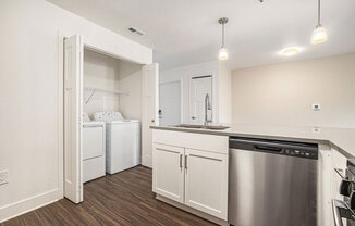 a white kitchen with a stainless steel dishwasher and a washer/dryer