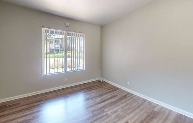 an empty living room with wood floors and a window