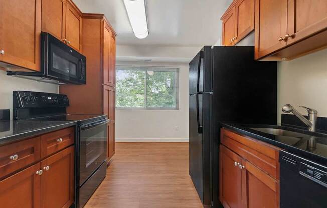 A kitchen with black appliances and wooden cabinets.