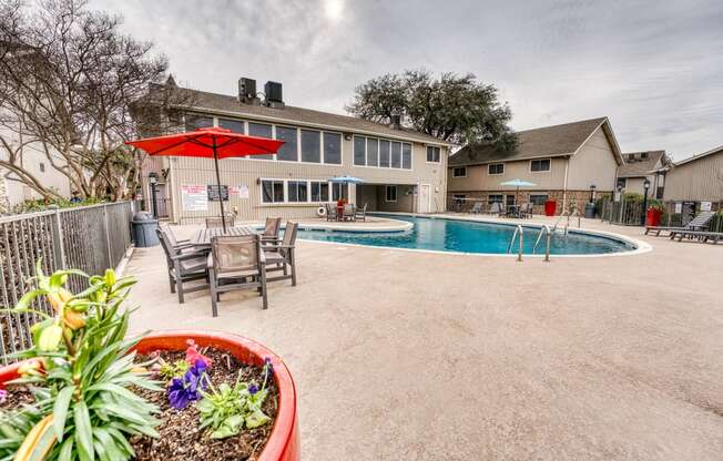 a backyard with a pool and patio with tables and umbrellas