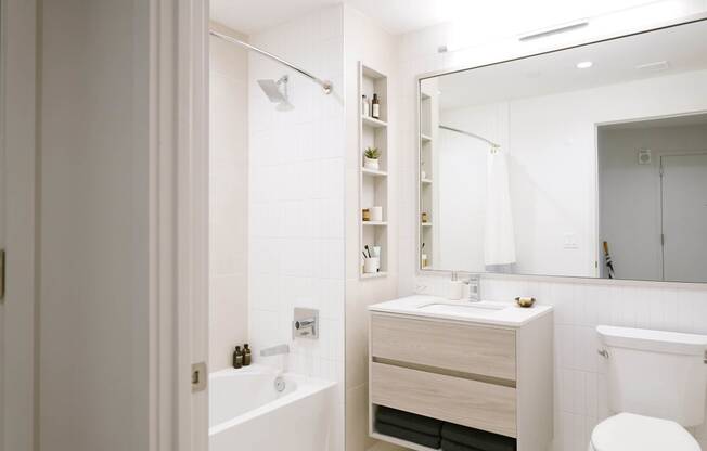 a white bathroom with a large mirror and a toilet and a sink at The Lively, Jersey City, 07302