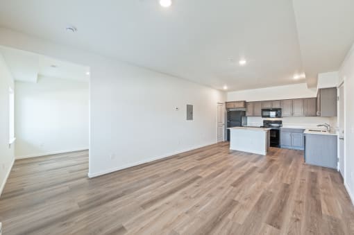 the living room and kitchen of an apartment with white walls and wood flooring at Gateway Apartments, Washington, 98802