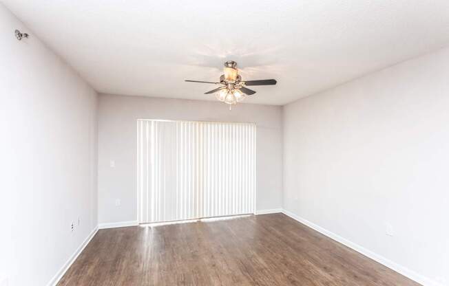 A room with a ceiling fan and wooden flooring.