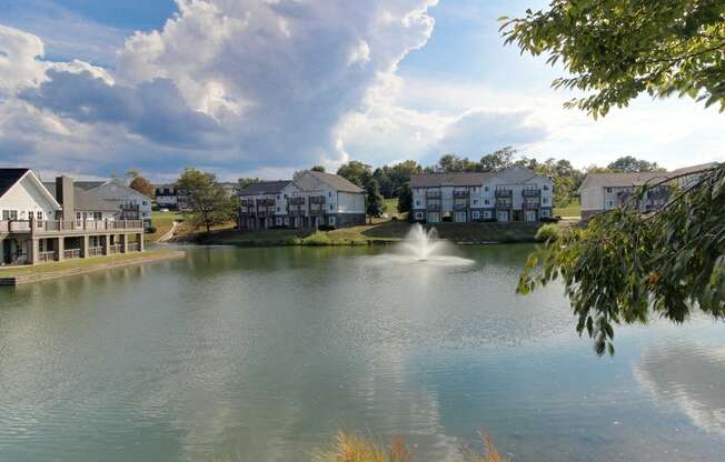 a pond with a fountain in front of some houses