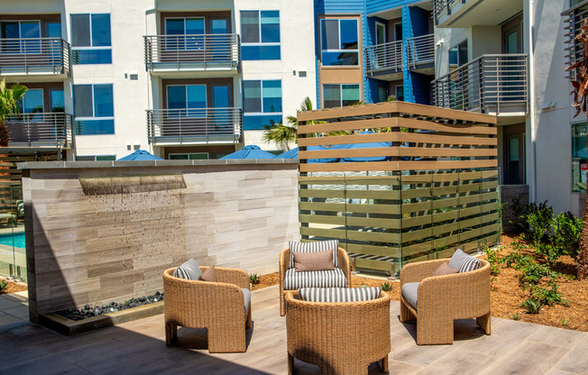 a patio with chairs in front of an apartment building