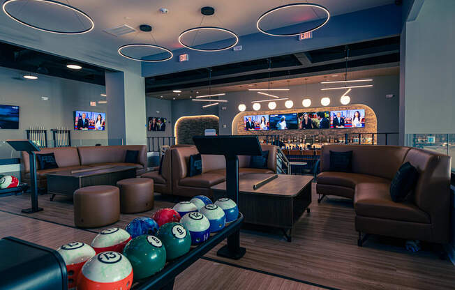 A bowling alley with a row of balls and chairs.