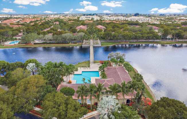 A house with a pool is surrounded by trees and is located near a body of water.