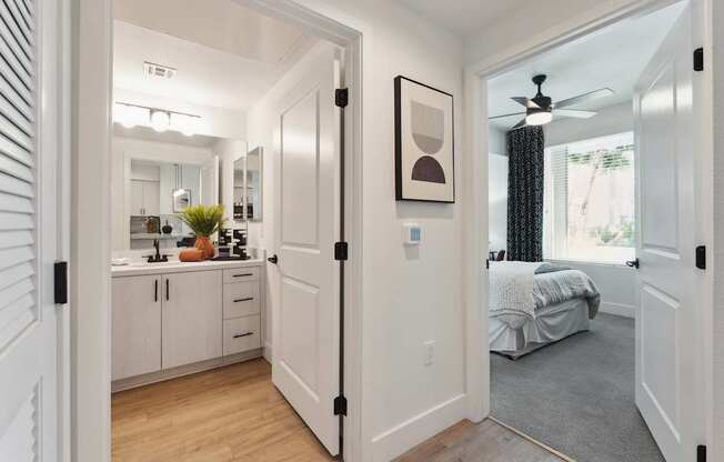 A white hallway with a bedroom at the end.