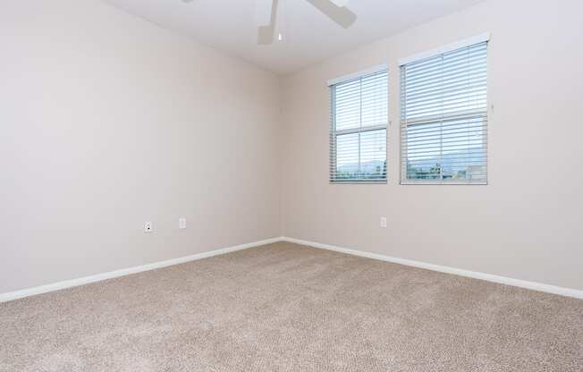 a bedroom with two windows and a ceiling fan