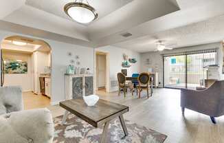 A living room with a grey couch, a coffee table, and a dining table with chairs.