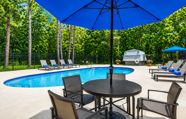 A pool area with a table and chairs and an umbrella.