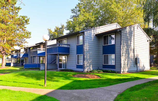 a blue and white apartment building with green grass and trees