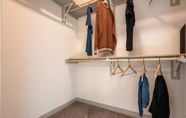 a well lit closet with coats hanging on a rack