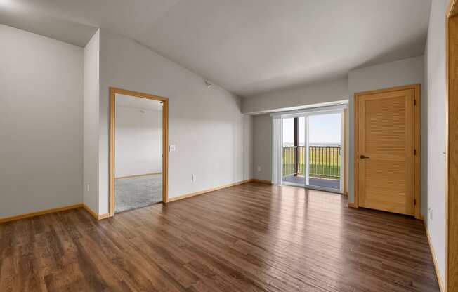 a bedroom with hardwood floors and a sliding glass door leading to a balcony