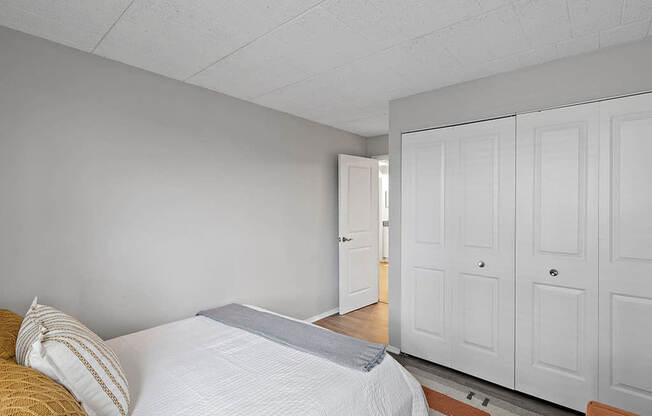 A bedroom with a bed, pillows, and a wooden floor.