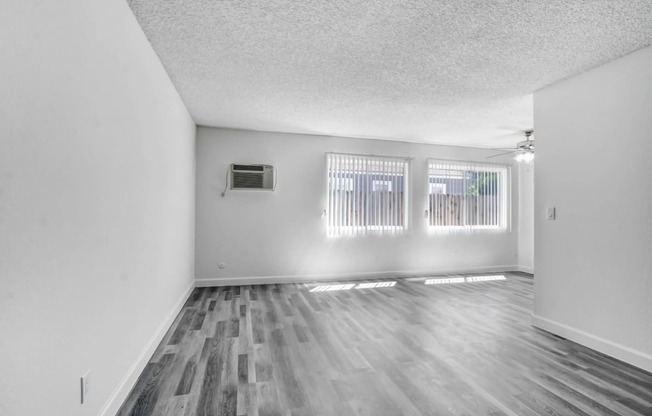 an empty living room with three windows