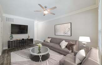 a living room with a couch and a table and a ceiling fan