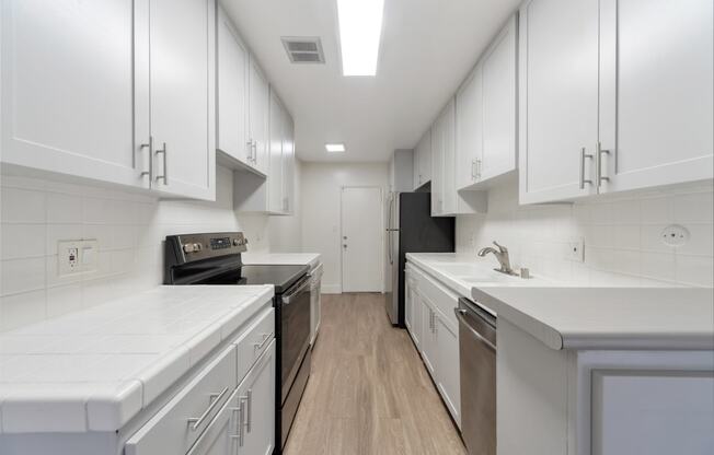 a kitchen with white cabinets and stainless steel appliances and white counter tops