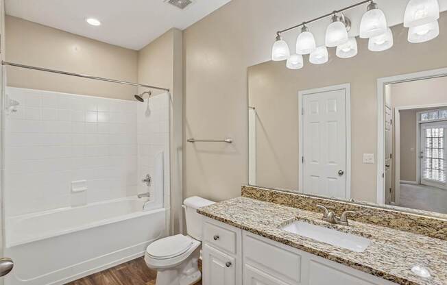 A bathroom with a white toilet, sink, and shower.