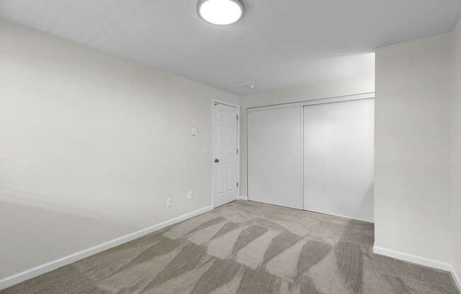 a bedroom with white walls, gray carpet, and overhead lighting at Swiss Gables Apartment Homes, Kent, 98032