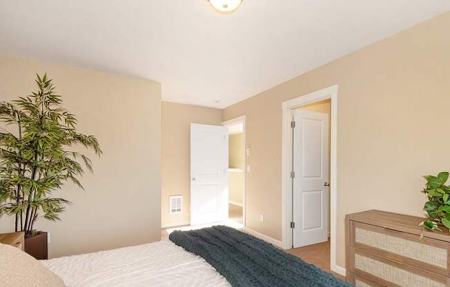 A bedroom with a bed, a potted plant, and a wooden dresser at The Landing Apartments and Townhomes, Oregon, 97045