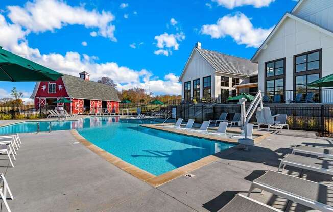 A large swimming pool with lounge chairs and a white building in the background.