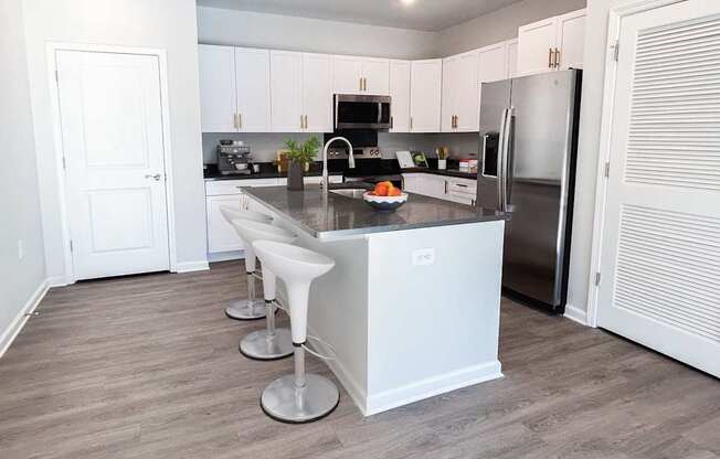 A kitchen with white cabinets and a stainless steel refrigerator.