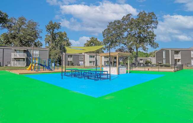 Picnic and BBQ area in blue and green surface and a yellow canopy at Maplewood apartments in Shreveport, LA.