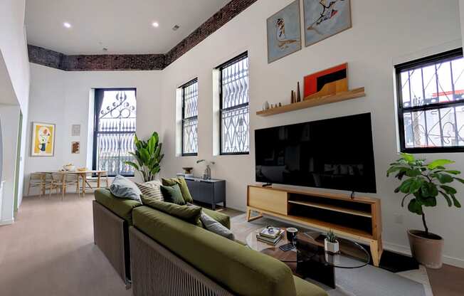 A living room with a green couch and a flat screen TV.