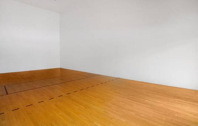 an empty room with wooden floors and a white wall