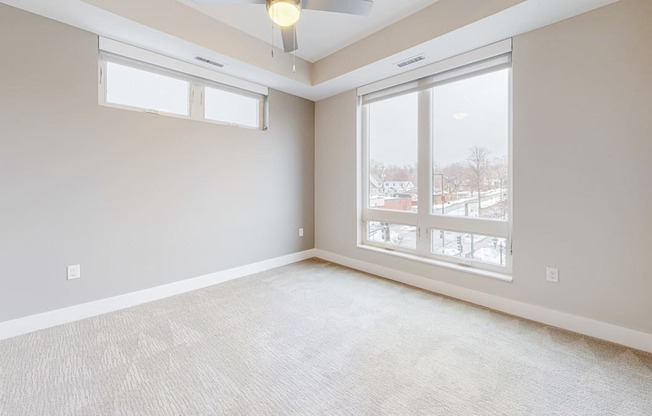 A room with a carpeted floor and a ceiling fan.
