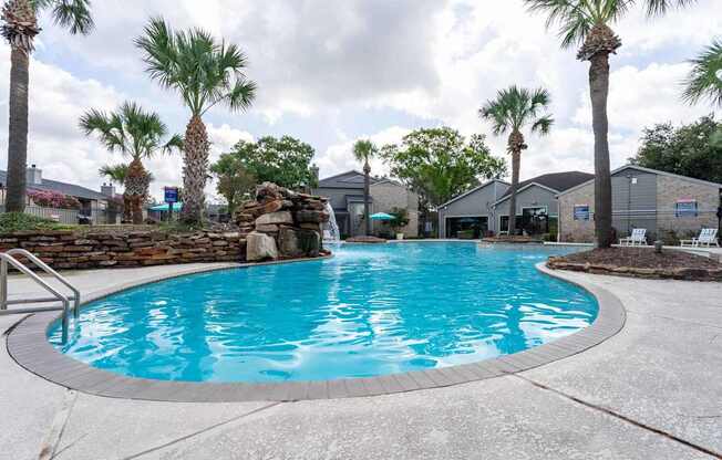 A swimming pool surrounded by palm trees and a stone wall.