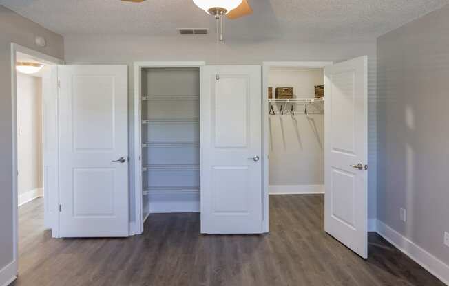 an empty closet with white doors and a mirrored closet door