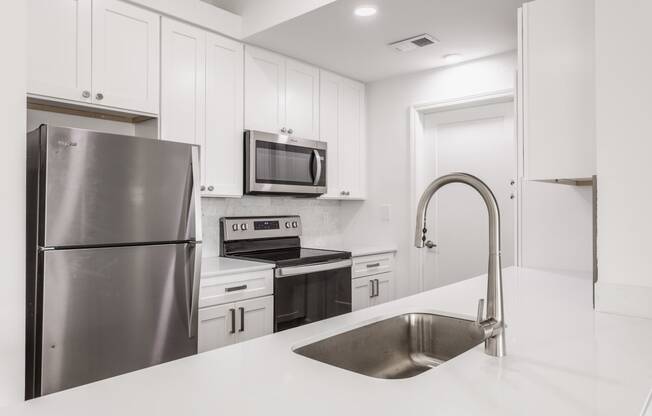 a white kitchen with stainless steel appliances and a sink