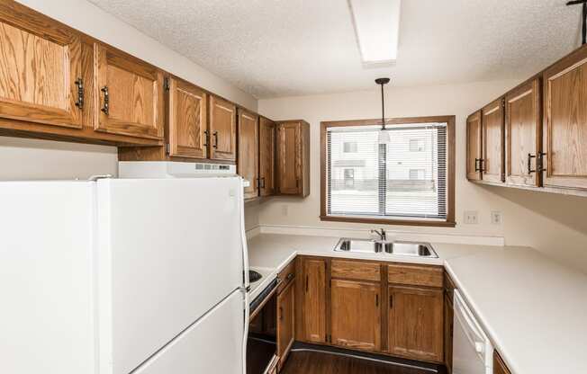 Grand Forks, ND Richfield Apartments. A kitchen with white appliances and wooden cabinets