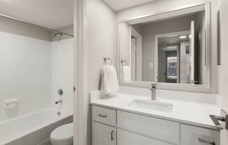 Contemporary bathroom with white vanity, framed mirror, and tub-shower combination at Heritage at Valley Ranch.