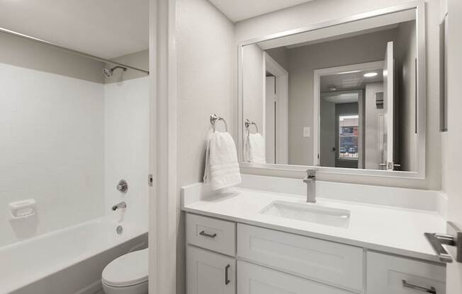 Contemporary bathroom with white vanity, framed mirror, and tub-shower combination at Heritage at Valley Ranch.
