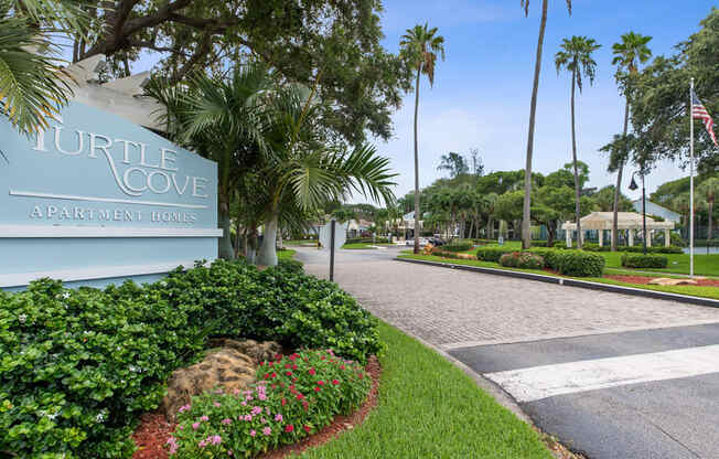 the entrance to turtle cove apartments with palm trees and a sign