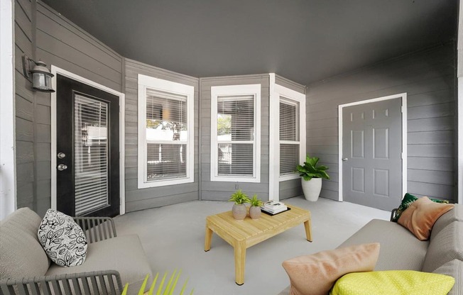 A living room with a grey couch, a wooden coffee table, and a grey wall. at Somerset Oaks Apartment Homes, Olathe